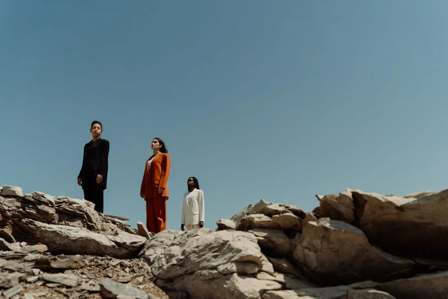 An outdoor fashion study with three people and an open sky
